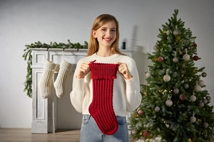Detail of red knitted Christmas stocking with folded cuff held in a festive setting