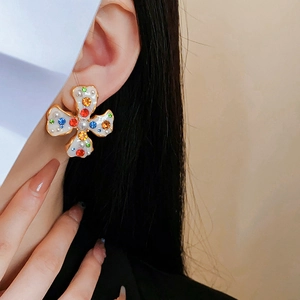 Detail of vintage flower earrings with colorful gems and imitation pearls on ear