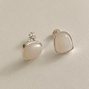 Macro detail of minimalist 925 sterling silver stud earrings with moonstone inlays