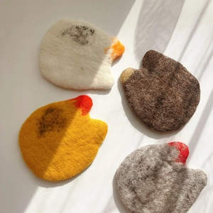 Detail view of four handmade wool felt coasters in animal shapes with fiber texture