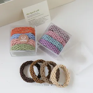 Close-up of honeycomb textured hair ties in pastel colors within a clear storage box