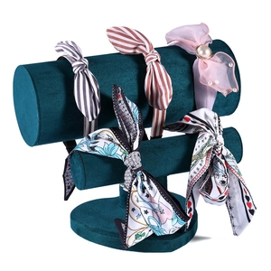 Three-tier green velvet headband display stand holding assorted stylish hair accessories