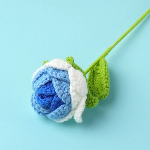 Detail of blue and white crochet rose with green leaves on light blue background
