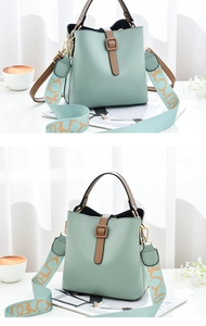 Detail view of mint green bucket bag featuring a brown leather strap and contrast design