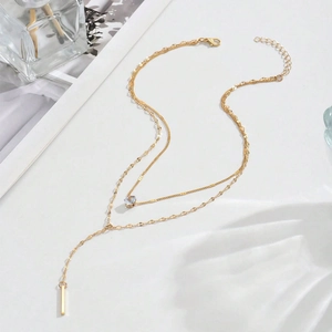 Double-layered gold Y-necklace featuring a sparkling zircon stone and a sleek vertical bar pendant