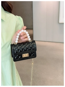 Mini black quilted crossbody bag featuring a pearl handle and golden chain strap