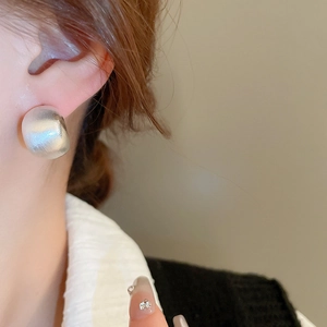 Close-up of minimalist brushed silver-tone C-shape stud earring on a model