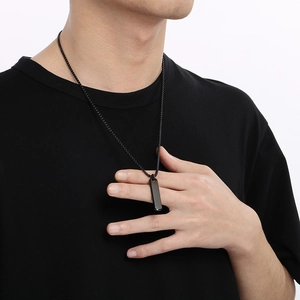 Close-up of a man wearing a sleek black geometric rectangular pillar pendant necklace