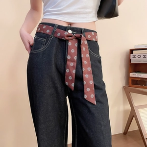 Dettaglio dei jeans in denim a vita alta con cintura in seta marrone a pois coordinata