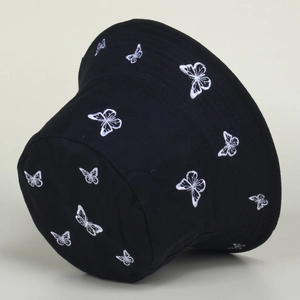 Close-up of intricate white butterfly embroidery on a black canvas bucket hat fabric