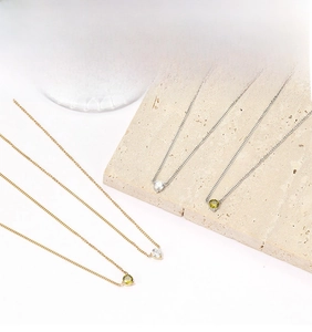 Detailed display of minimalist gold and silver zircon pendant necklaces on textured stone