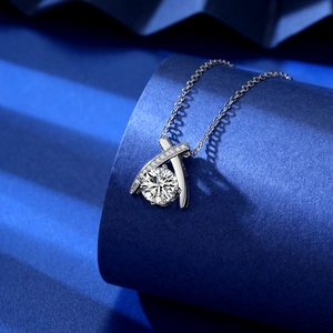 Macro shot of 2ct round zircon cross pendant on dark blue cylindrical display stand