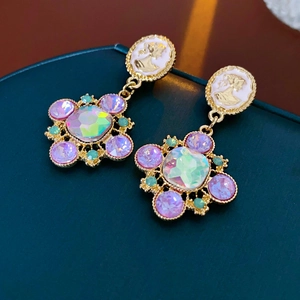 Detail of vintage gold flower earrings with purple crystals and embossed portrait