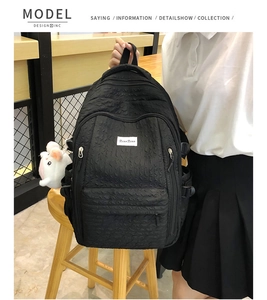 Détail du sac à dos noir texturé avec étiquette XiaoXiao et petit pendentif en peluche