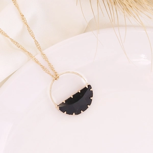 Gold chain necklace with black crescent moon pendant on white ceramic and silk decor