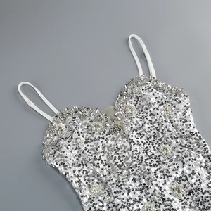 Dettaglio di paillettes argento, perle bianche e strass scintillanti sullo scollo a V