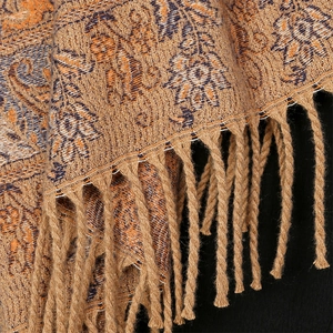 Detailed macro shot of paisley pattern fabric and orange fringe on a winter scarf
