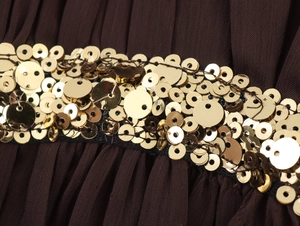 Macro shot of dark brown pleated fabric with golden sequin ribbon and detailed texture