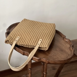 Vintage plaid cotton tote bag with leather handles on a retro wooden table
