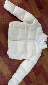 Close-up of white quilted jacket with woven texture pattern and front zipper detail