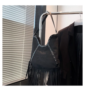 Detail of vintage black fringe tote bag featuring sun face embossed design and metal studs