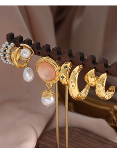 Collection of gold vintage earrings with pearls and colorful zircons on a wooden display