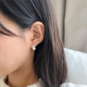 Close-up of minimalist sterling silver pearl earring worn on the earlobe with soft lighting