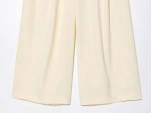 Vue détaillée macro du pantalon large beige montrant la texture en tricot et l'ourlet net