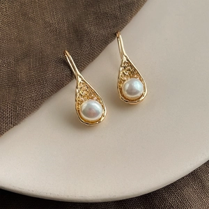 Macro detail of French vintage baroque pearl drop earrings with textured golden lava frames
