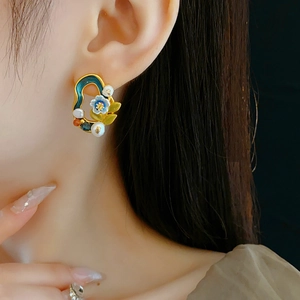 Close-up of vintage gold floral earring with freshwater pearls and colorful enamel detail