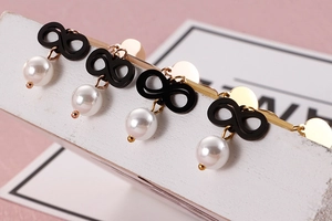 Detailed macro view of infinity symbol gold earrings with white pearl accents