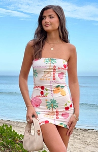 Outdoor shot of a strapless mini dress with vibrant tropical fruit and palm prints