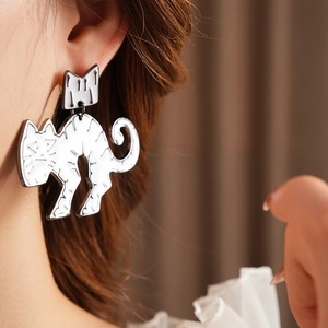 Close-up of minimalist silver cat stud earrings worn by a model in soft lighting