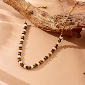 Golden chain necklace with tiger eye beads displayed on natural wood background