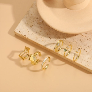 6-piece gold adjustable ring set with stars and zircons on a beige stone platform