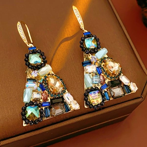 Detail of vintage triangular earrings with colorful zircon stones in gold finish