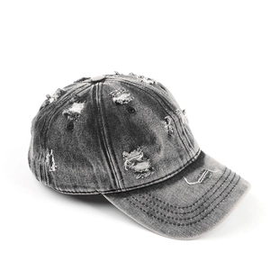 Detailed close-up of distressed denim baseball cap with vintage frayed holes and worn edges