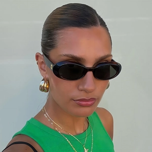 Detail of oval retro sunglasses with gold logo on temple and luxury accessories