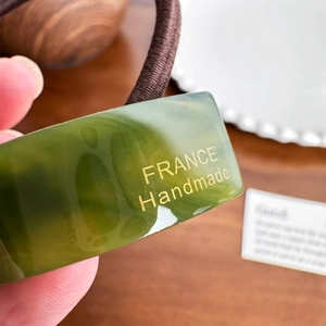 Minimalist green acetate ponytail holder with a gold France Handmade label detail