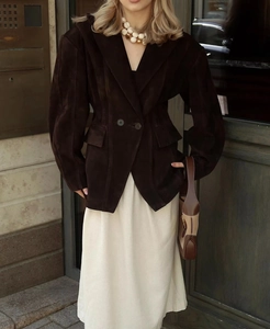 Détail d'une veste cintrée en suédine marron foncé avec ceinture et collier de perles