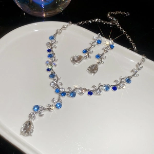 Detailed view of silver flower necklace and teardrop earrings with blue crystals