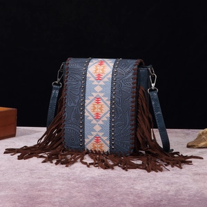 Macro detail of embossed blue leather crossbody bag with ethnic fringe and silver rivets