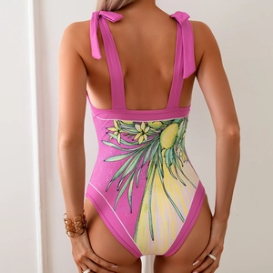 Detail of pink floral one-piece swimsuit featuring tropical print and lace-up back straps