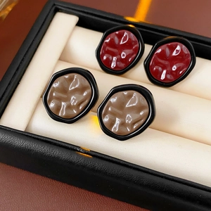 Detail of minimalist irregular earrings in red and brown resin with glossy texture