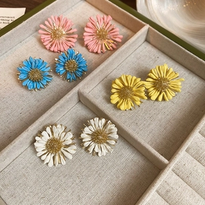 Detail of four pairs of colorful daisy earrings in pink, blue, yellow, and white colors