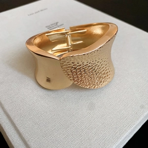 Detail of golden hammered texture and smooth finish on oval open bangle bracelet