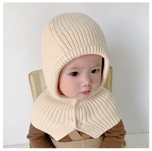 Macro detail of cream knit baby hooded scarf with thick texture and white button closure