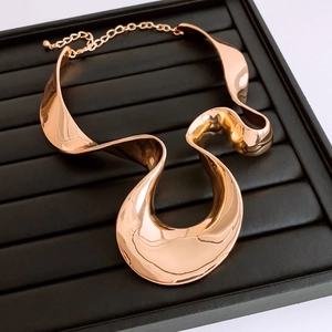 Detail of rose gold wavy choker necklace with polished metallic texture and lobster clasp