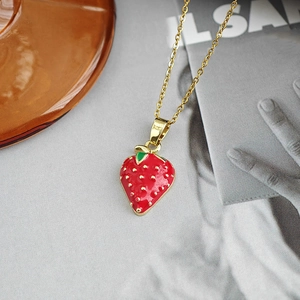 Détail macro du pendentif fraise en émail rouge et sa fine chaîne dorée élégante pour femme