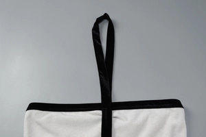 Détail du tricot blanc côtelé avec bride licou en velours noir et bordure contrastée